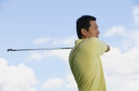Man swinging golf club, looking away - Alex Mares-Manton