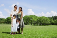Family of four standing in field, looking at camera - Alex Mares-Manton