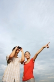 Man using binoculars, woman standing beside him, pointing in the distance - Yukmin