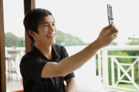 Man in cafe using mobile phone to take a picture of himself - Yukmin