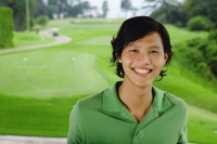 Man in green polo shirt, smiling at camera, golf course behind him - Yukmin
