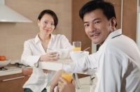 Couple sitting in kitchen with breakfast, looking at camera - blueduck