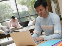 Man using laptop, woman in background reading - blueduck