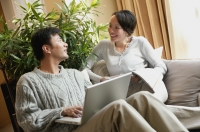 Couple in living room, man with laptop, woman holding magazine - blueduck