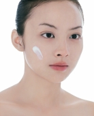 Young woman, head shot, dab of moisturizer on face - blueduck