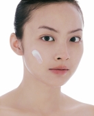 Young woman looking at camera, dab of moisturizer on face - blueduck