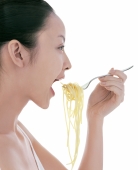 Young woman eating spaghetti, side view - blueduck