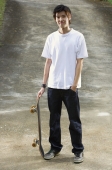 Young man with skateboard, hand in pocket - Yukmin