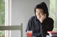 Young man with hooded jacket, drink in front of him, smiling - Yukmin