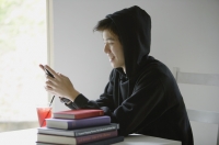 Young man with hooded jacket, looking at mobile phone - Yukmin