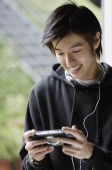 Young man looking at MP3 player, smiling - Yukmin
