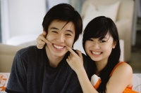 Teenage couple sitting side by side, smiling at camera - Yukmin
