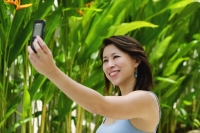 Woman outdoors, using mobile phone to take a picture of herself - Yukmin