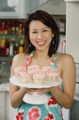 Woman holding tray with cupcakes - Yukmin