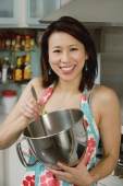 Woman in kitchen, holding mixing bowl - Yukmin