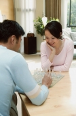 Couple sitting at table at home playing chess - blueduck