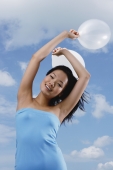 Woman holding balloons in air, smiling at camera - Yukmin