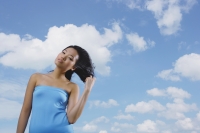 Woman in blue tube top, standing against blue sky - Yukmin