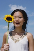Woman holding sunflower stalk, portrait - Yukmin