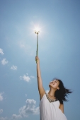 Woman holding sunflower stalk up in air - Yukmin