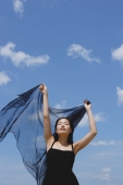 Woman in black dress, eyes closed, holding scarf in air - Yukmin