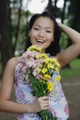 Young woman holding bouquet of flowers, hand on head, smiling at camera - Yukmin
