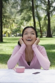 Young woman sitting outdoors, listening to MP3 player - Yukmin