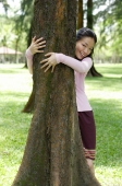 Young woman with arms around a tree - Yukmin