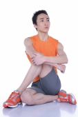 Young man sitting on floor, legs and arms crossed - blueduck
