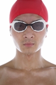 Young man wearing swimming goggles and swimming cap, face wet - blueduck
