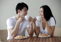 Couple having breakfast, smiling at each other - Yukmin