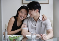 Couple at home, sitting by dining table, woman looking at camera - Yukmin