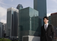 Businessman looking at camera, cityscape in the background - Yukmin