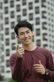 Man smiling at camera, making hand sign - Yukmin
