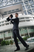 Businessman lifting briefcase in air, smiling at camera - blueduck