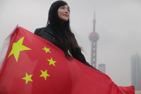 Woman holding China flag, Oriental Pearl TV Tower in the background - blueduck
