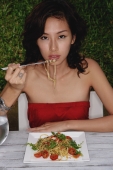Woman sitting in restaurant eating noodles with chopsticks - Yukmin