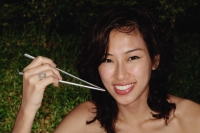 Woman holding chopsticks, looking at camera, smiling - Yukmin