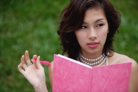 Woman wearing necklace and writing in pink journal - Yukmin