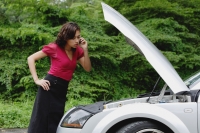 Woman on mobile phone while checking engine of car, hood up, side of road - Yukmin