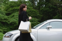 Woman walking to car, carrying shopping bags, looking over shoulder at camera - Yukmin