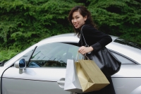 Woman carrying shopping bags, smiling at camera, getting into car - Yukmin
