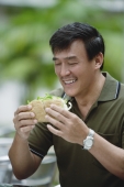 Man sitting in outdoor cafe eating sandwich - Yukmin