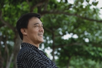 Man sitting in park, smiling - Yukmin