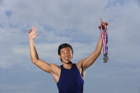 Man winning race, arms raised holding medals - Yukmin