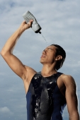 Man squeezing water bottle over face, cooling off after workout - Yukmin