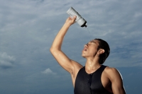 Man squeezing water bottle over face, cooling off after workout, hot - Yukmin