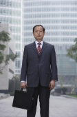 A businessman stands in the city with a briefcase - Alex Mares-Manton