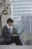 A businesswoman sits down and uses her laptop - Alex Mares-Manton