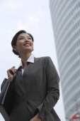 A businesswoman smiles as she stands in front of a skyscraper - Alex Mares-Manton